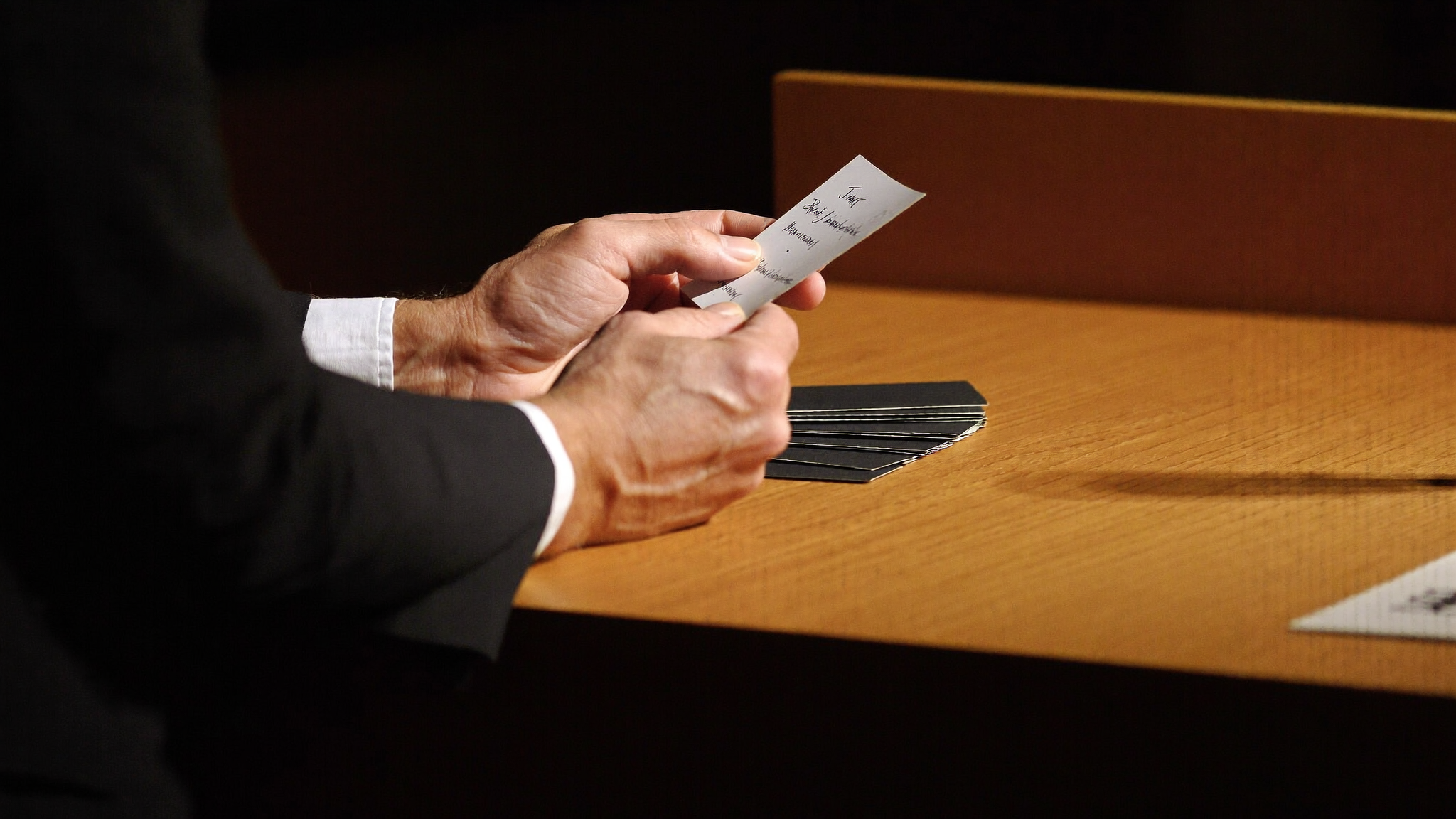 Close-up of a speaker's hands resting on a wooden lectern